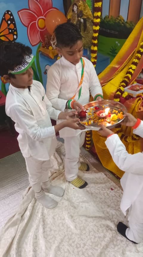 Children in white kurtas holding an aarti plate with lit diyas