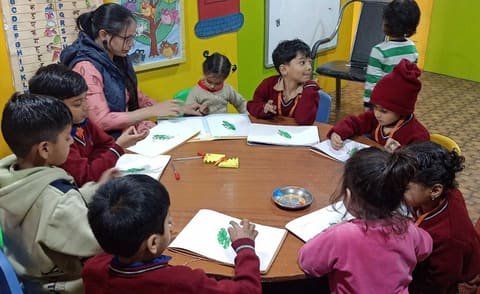 Children drawing at a round table with their teacher
