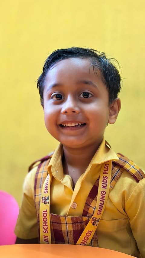 A cheerful boy in school uniform in a yellow-walled classroom