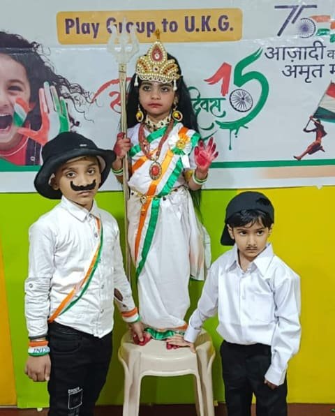 Children in fancy dress as Bharat Mata and freedom fighters in front of an Independence Day banner