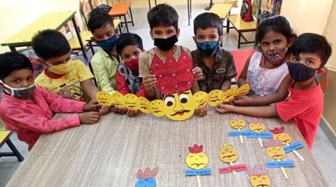 Children showing their paper craft at a classroom table
