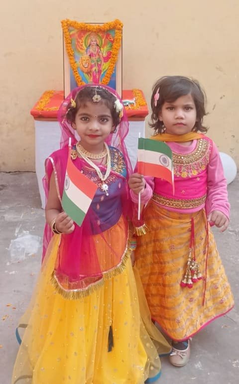Two girls in traditional dresses holding small Indian flags