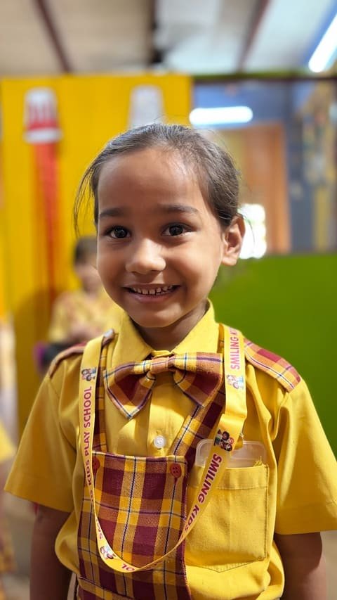 A smiling girl in the yellow and maroon school uniform