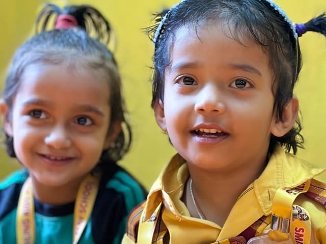 Two young children smiling at a classroom table